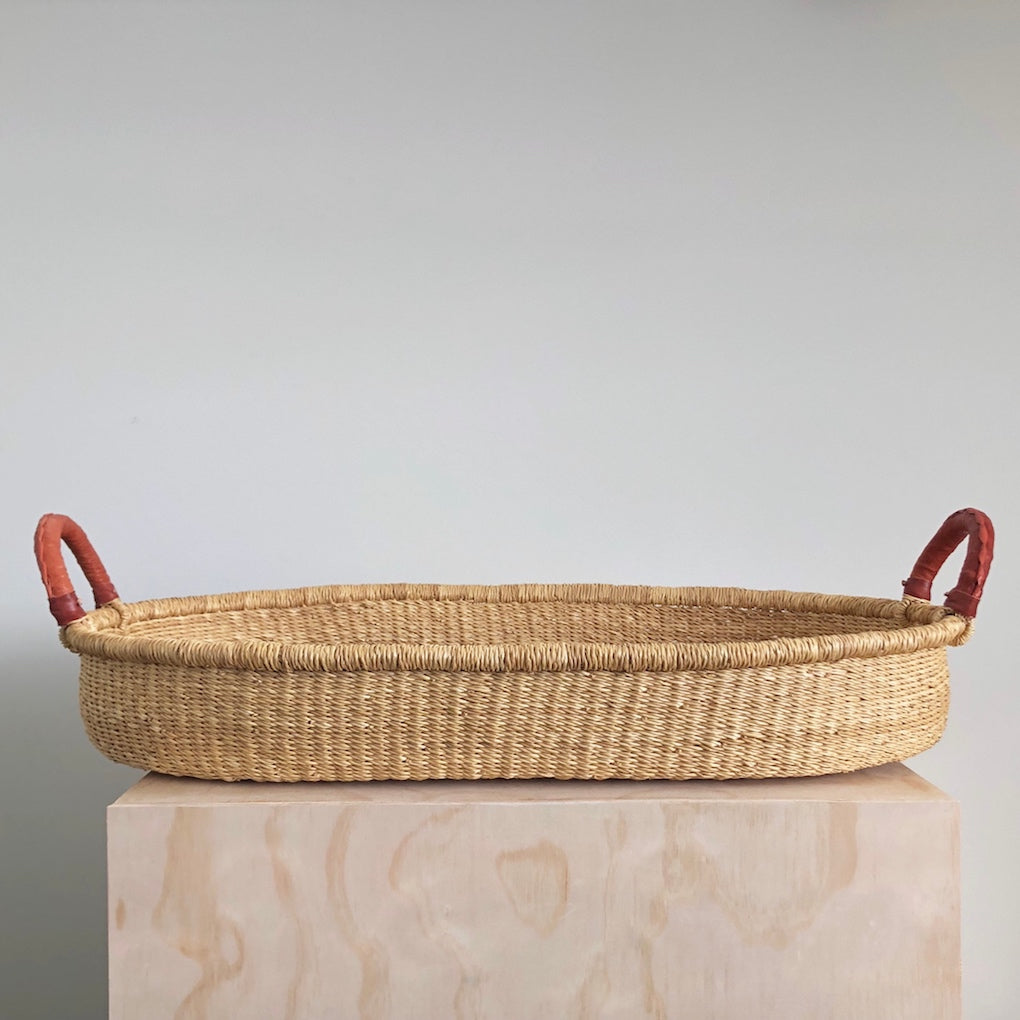 Woven African elephant grass changing basket on top of wooden display box
